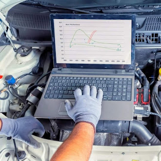 Technician running computer diagnostics on a vehicle engine