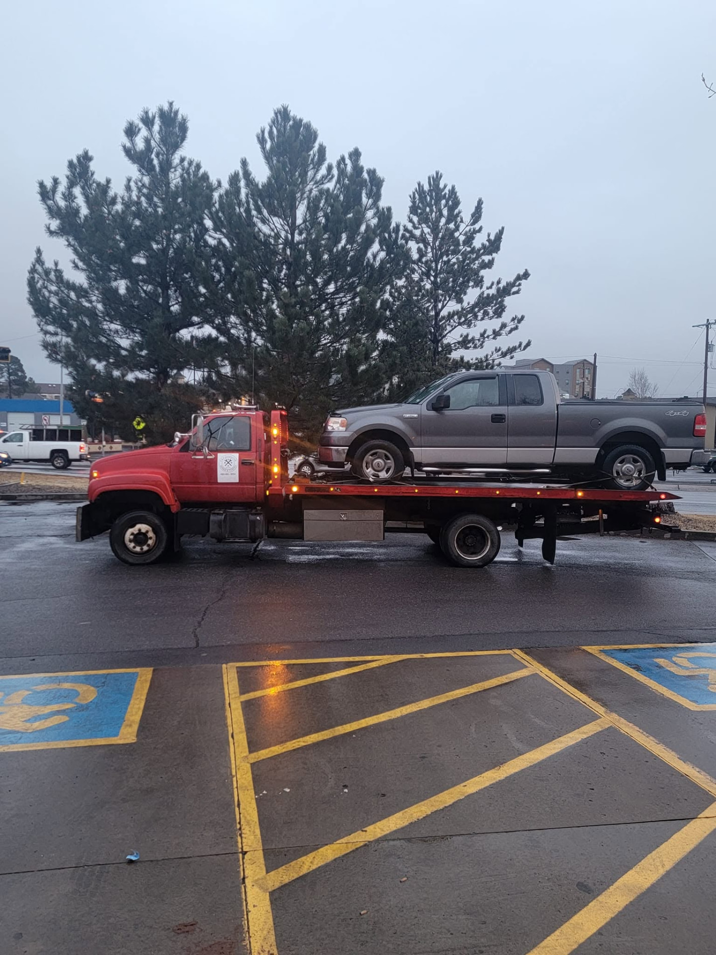 K&P red flatbed tow truck hauling a pickup truck through Holbrook, Arizona